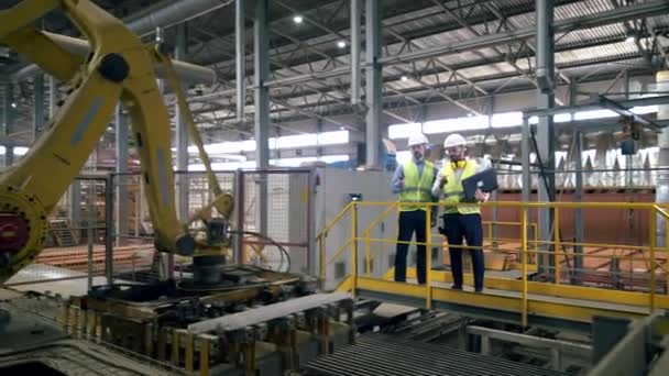 Planta productora de ladrillos con dos ingenieros trabajando con portátil — Vídeos de Stock