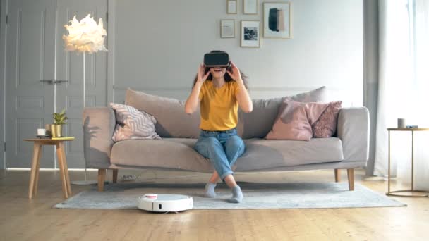 Smart Home concept. Robotic Hoover is het schoonmaken van het appartement met een vrouw in vr-bril — Stockvideo