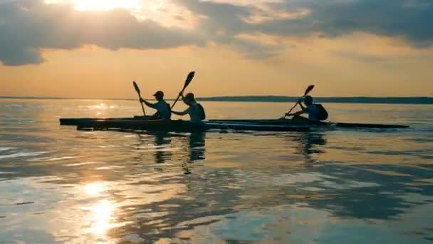 Atardecer río con gente cruzándolo en kayaks — Vídeo de stock