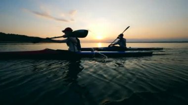 Kayıkçılar gün batımı sularında sürtücüler.
