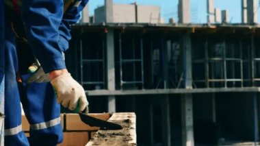 İşçi bir ev inşa ederken tuğla döşemek için çimento kullanır.