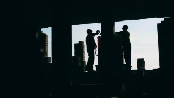 Les hommes posent des briques pendant qu'ils travaillent sur un chantier . — Video