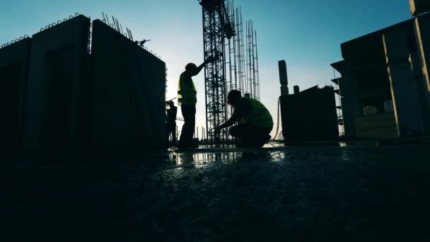 Arbetstagare som flyttar metall stolpar på en byggplats. — Stockvideo