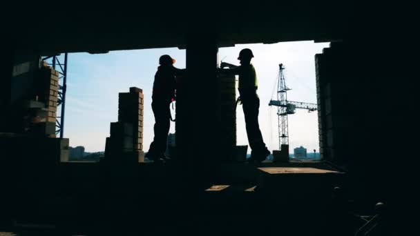 Arbetstagare i enhetliga tegelstenar på en byggplats. — Stockvideo