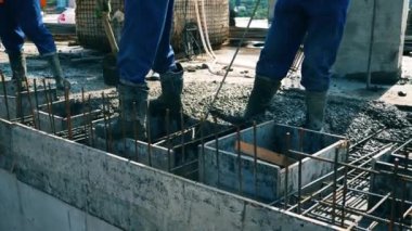 İnşaatçılar bir şantiyede çalışırken zeminde çimento seviyesine.