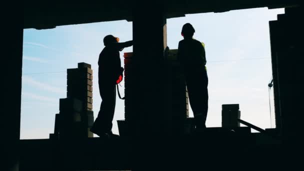 Professionele bouwers die werken met bakstenen aan een muur. — Stockvideo