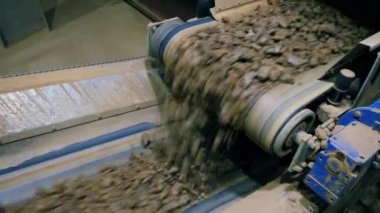 Fabrikada çalışan bir konveyörden düşen taşlar.