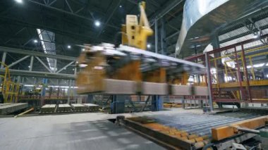 Otomatik makine, tuğlaları çalışan bir konveyörüzerinde hareket ettirir.