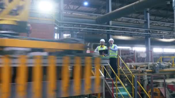 Kolegové z továrny kontrolují stroj, který pracuje s cihlami. — Stock video