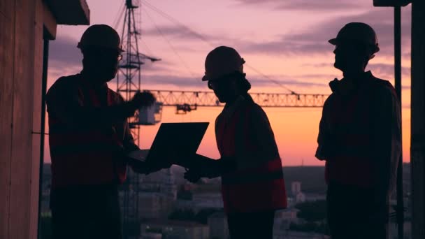 Groep ingenieurs praat op de bouwplaats van de zonsondergang — Stockvideo