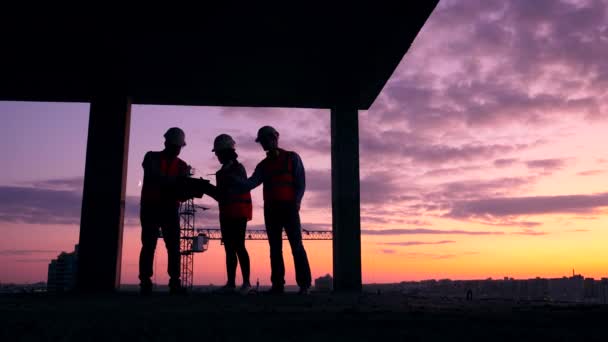 Stedelijke bouwplaats bij zonsondergang met technici die erin praten — Stockvideo