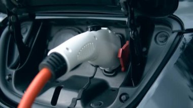 Modern şarj cihazı elektrikli bir arabaya takılı. Yenilikçi elektrikli hibrid araba şarj.