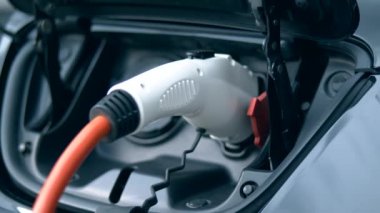 Bir istasyonda takılı kabloile şarj edilen bir elektromobil.