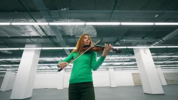 Vöröshajú hegedűművész játszik neki eszköz egy teremben — Stock videók
