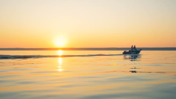 Motorboot mit mehreren Personen liegt bei Sonnenaufgang weit entfernt in einem Wasserreservoir — Stockvideo