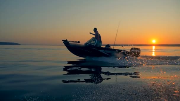 Un pêcheur pointe du doigt quelque chose en naviguant avec un autre au lever du soleil — Video