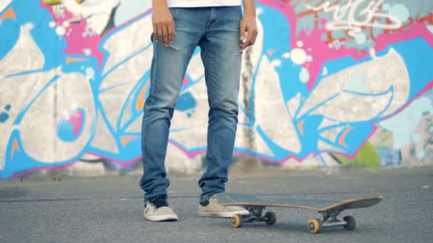 Man lyfter sin skateboard med benen och griper tag i den. 4K. — Stockvideo