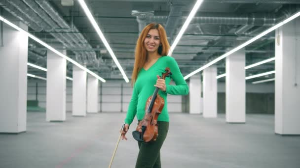 Женщина со скрипкой улыбается и уходит. — стоковое видео