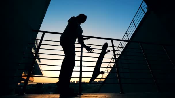 Een man neemt zijn skateboard op een zonsondergang achtergrond, Bottom View. — Stockvideo