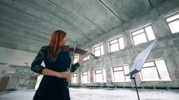 Женщина-скрипачка играет, глядя на музыкальную стойку — стоковое видео