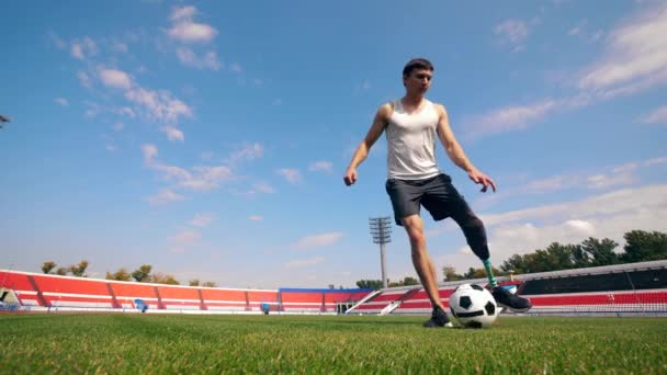 Un hombre con una pierna protésica está jugando con una pelota — Vídeo de stock