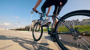 Bisiklete protez bacaklı bir kişi bindiriliyor.