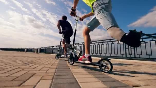 Protez bacaklı insanlar yol boyunca scooter sürüyorlar. — Stok video