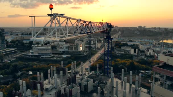 Déménagement de la grue de chantier sur le site du projet Sunset. Site de construction moderne au coucher du soleil, vue aérienne . — Video