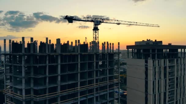 Οικοδομικά μηχανήματα και ψηλά σπίτια σε εξέλιξη κατά το ηλιοβασίλεμα — Αρχείο Βίντεο