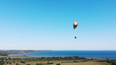 Bir insan gökyüzünde bir yamaç paraşütü ile uçar.