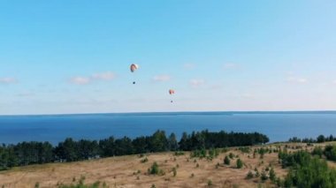 İnsanlar gökyüzünde yamaç paraşütleriyle uçarlar..