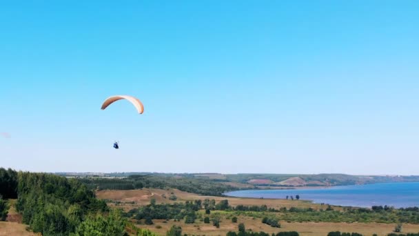 Una persona con un paraavión volando en el cielo . — Vídeos de Stock