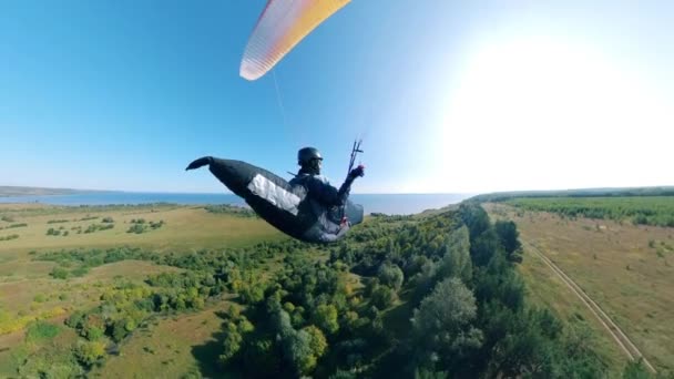 Un sportif volant avec un planeur au-dessus de champs avec des arbres . — Video