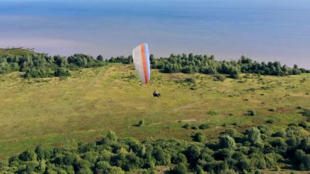 Sportovec plující s paraglideru přes pole. — Stock video