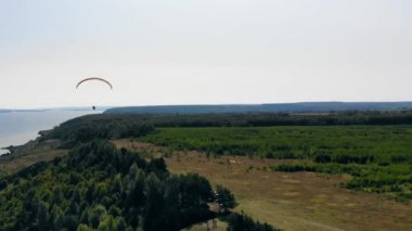 Sporcu tarlalarda antrenman yaparken planörle uçuyor.