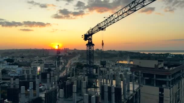 Site de construction au coucher du soleil. Le chantier urbain et les grues et le paysage urbain du coucher du soleil — Video