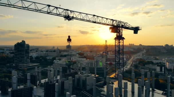 Bouw kraan en meerverhaal huis in uitvoering bij zonsondergang — Stockvideo