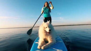 Genç bir kadınla kürek çekerken bir köpek havlıyor.
