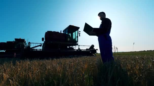 Agrónomo trabaja con un ordenador portátil en un campo . — Vídeos de Stock