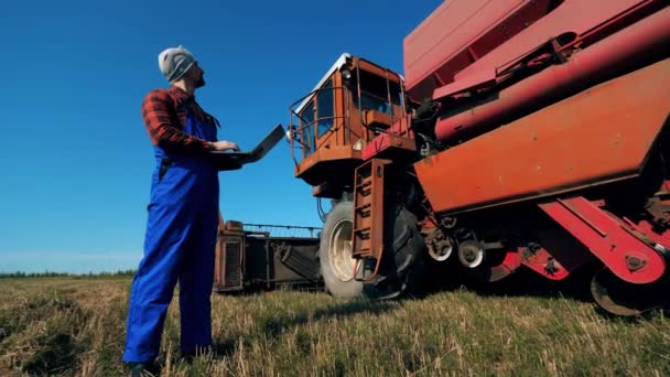 Hombre agrónomo comprueba tractor grande en un campo . — Vídeos de Stock
