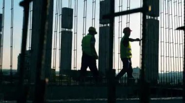 İki işçi inşaat alanına metal yapı döşedi.