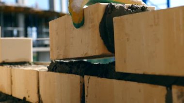 Bricklayer doing brickwork at a construction site. A bricklayer works at a site, using trowel.