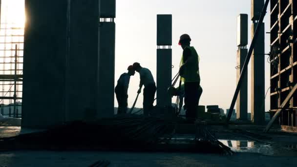 Mannen die metalen palen bewegen terwijl ze een huis bouwen. — Stockvideo