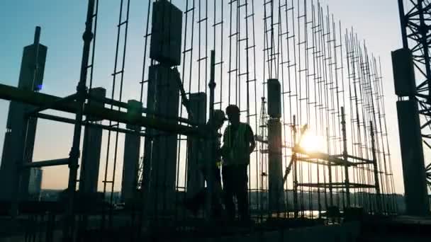 Ingenieros trabajan en un sitio de construcción, instalando postes . — Vídeo de stock