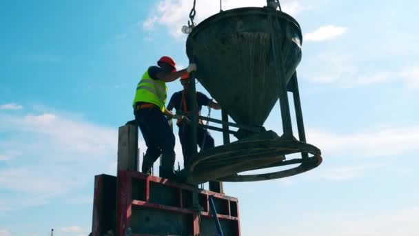 Stavbaři pracují s cementovým kontejnerem, připevňují ho k jeřábovým lanům. — Stock video