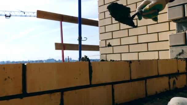 Una persona pone ladrillos mientras construye una casa. Albañil haciendo ladrillos en una obra de construcción . — Vídeo de stock