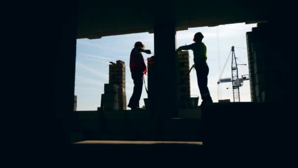 Los hombres ponen ladrillos mientras trabajan en un sitio. Albañil haciendo ladrillos en una obra de construcción . — Vídeo de stock