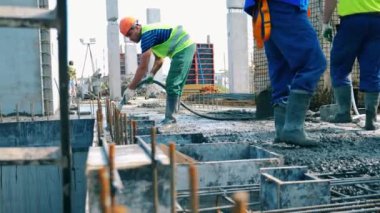 Builders work with concrete on construction site.