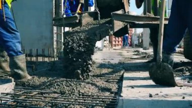 İnşaatçılar inşaat alanında çalışırken zemine ıslak beton dökerler..