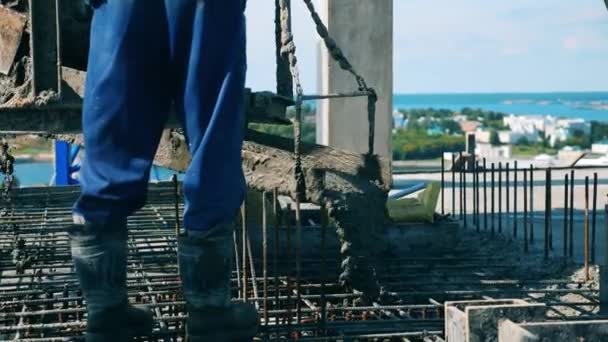 Mann gießt auf Baustelle nassen Zement auf Fußboden. — Stockvideo